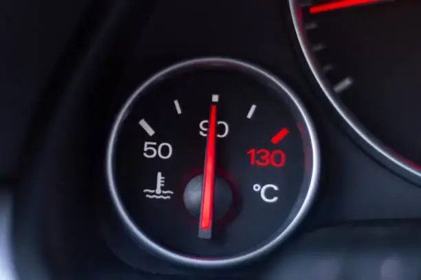 Close-up of a car temperature gauge indicator showing engine temperature between C and H on a vehicle dashboard.